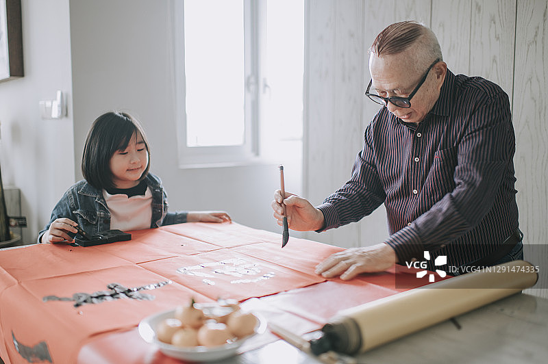 亚洲华人小女孩帮助和学习她的祖父写中国书法图片素材