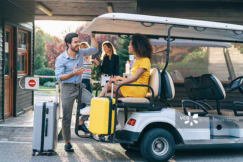 一对夫妇用高尔夫球车提着行李离开了酒店图片素材