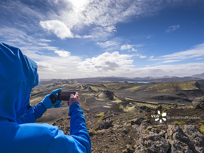 冰岛拉卡加，一名男子在阳光明媚的日子里用智能手机拍摄风景图片素材