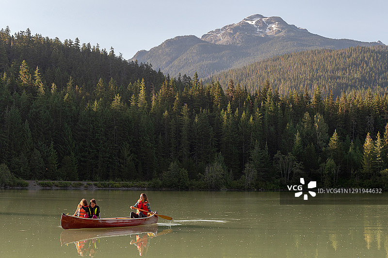 一家人在美丽的山湖上划独木舟图片素材