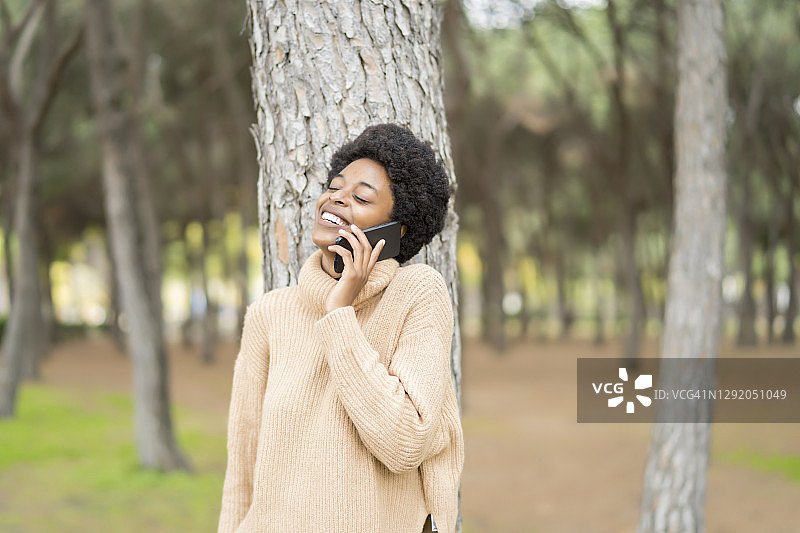 非洲女性，留着非洲式发型，用智能手机说话图片素材