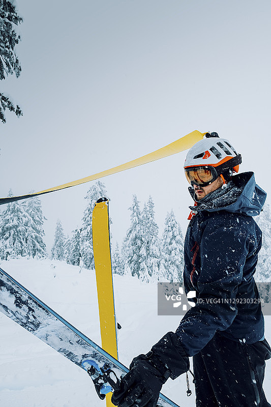 在一个暴风雨的冬日里，一个偏远地区的男性滑雪者正在从他的滑雪板上剥皮图片素材