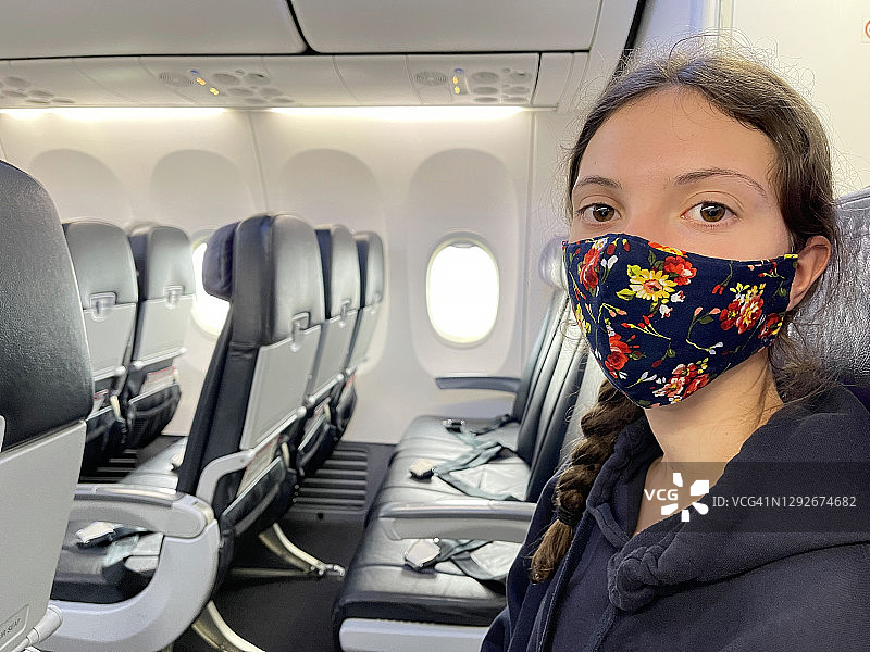 航空旅行、带花卉口罩的年轻人、空飞机座位、COVID-19大流行图片素材