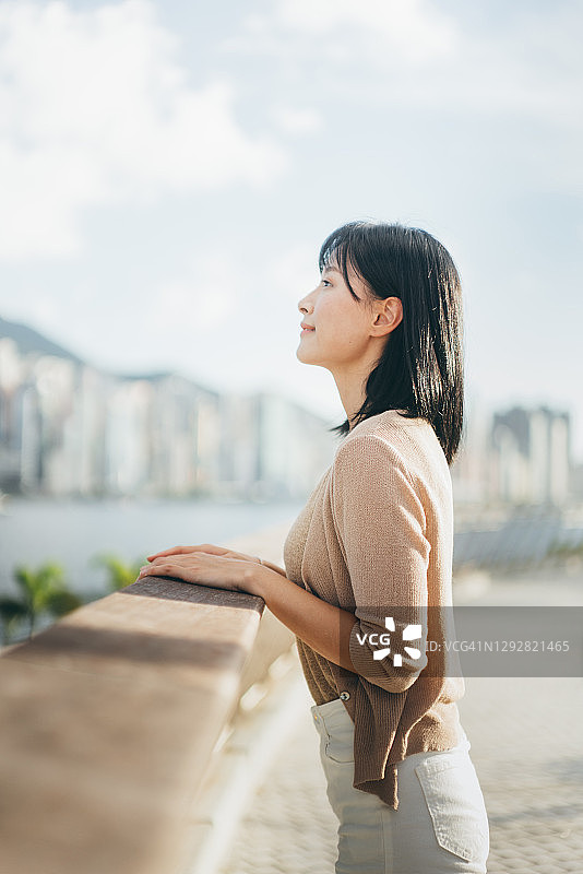 无忧无虑、安详的年轻亚洲女子仰望天空，在公园里放松，享受阳光图片素材