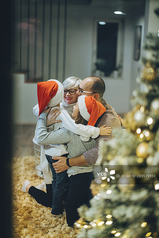 父母抱着两个孩子戴着圣诞老人的帽子图片素材