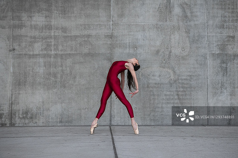 在法国里昂，女芭蕾舞者穿着红色紧身衣和尖头鞋在街道上跳舞图片素材
