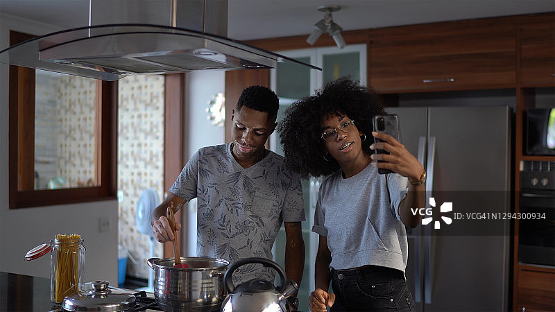 年轻夫妇或兄弟姐妹在家做饭时打视频电话图片素材