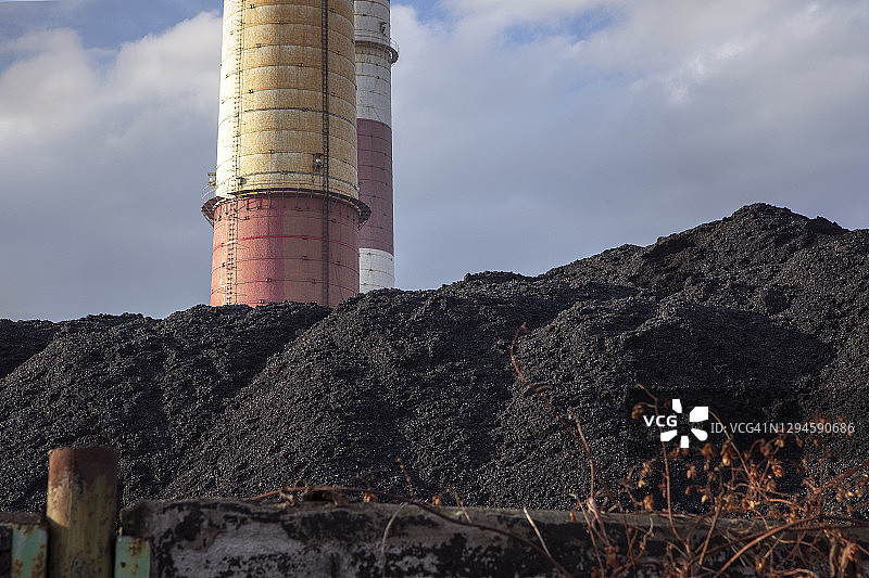 煤堆，天然黑煤与工业烟囱。工业景观。全球变暖，二氧化碳排放，煤炭能源问题。图片素材