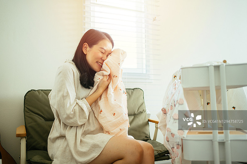 亚洲年轻的母亲感到高兴网上购物和准备布新生儿到来图片素材