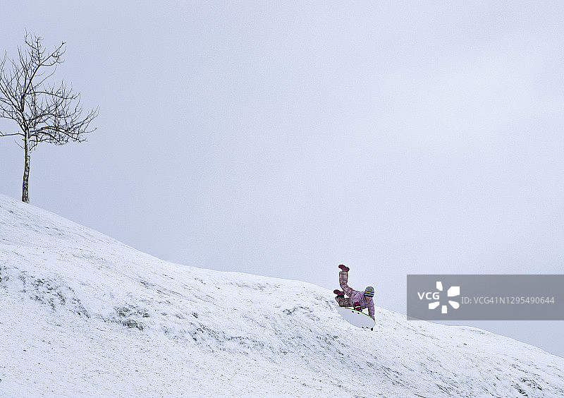 一个男孩，一个孩子从白雪覆盖的山上高速滑下来，飞到跳板上。冬天好玩的周末。图片素材