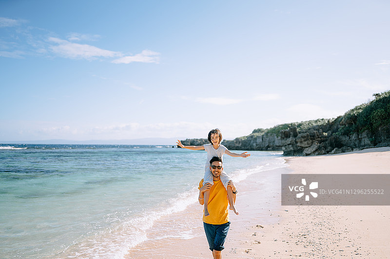 快乐的父亲背着小女儿在海滩上图片素材