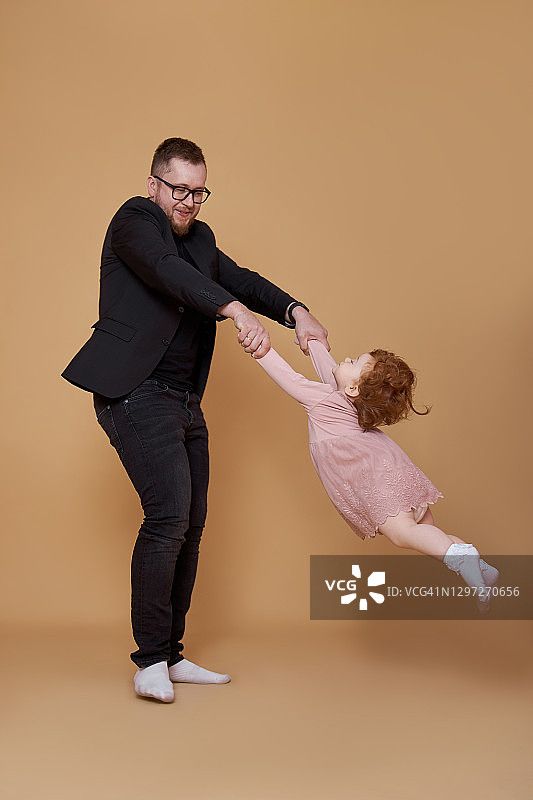 爸爸牵着小女儿的手。一个男人和一个女孩玩。家庭度假图片素材