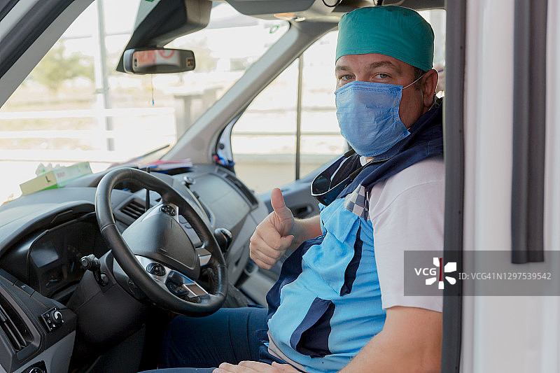 戴面罩的男性急救护理人员在疫情期间驾驶救护车图片素材