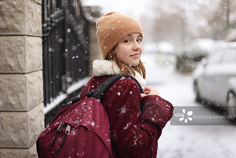一个女孩在下雪的街道上上学图片素材