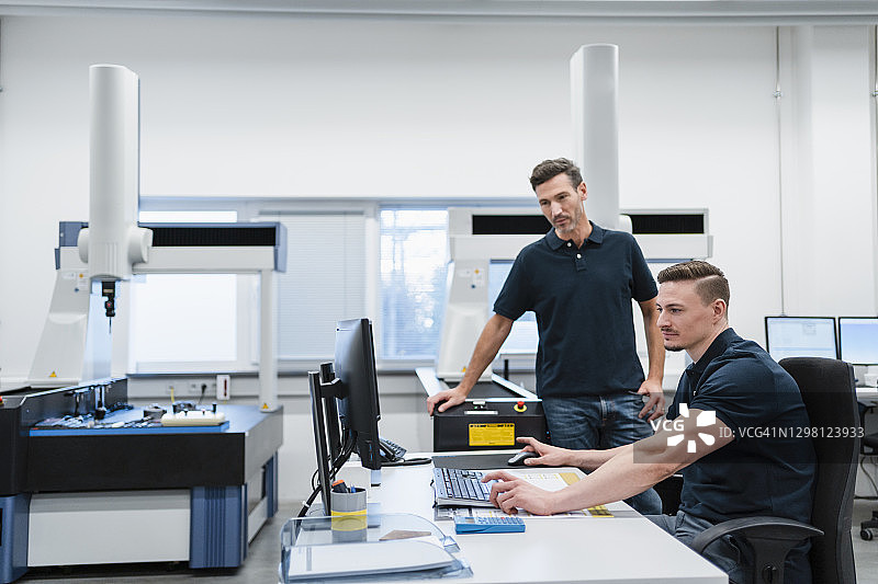 男技术员与同事在工业办公室使用电脑图片素材