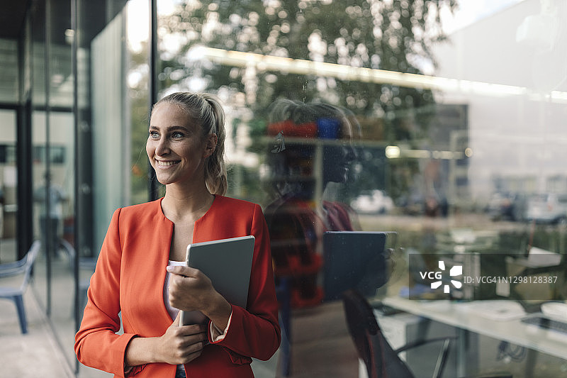 快乐的女性企业家在办公室外拥有数字平板电脑图片素材