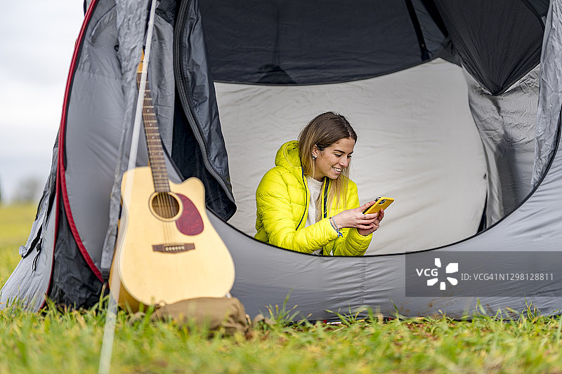 一名年轻女子在帐篷里使用智能手机图片素材