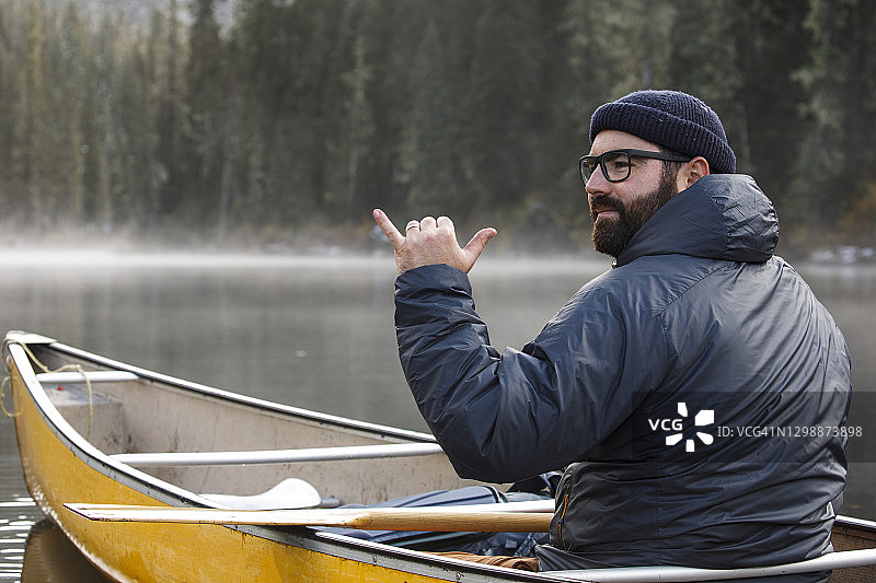 有雾的日子，兴奋的男子在湖上划独木舟图片素材