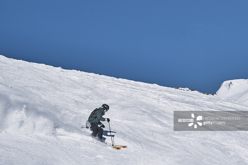 一个正在进行高山滑雪的人从契格山的雪坡上滑下来。图片素材