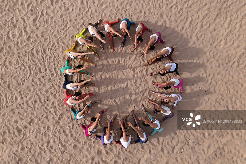 团队合作理念。一群女人在海滩上练习瑜伽。图片素材