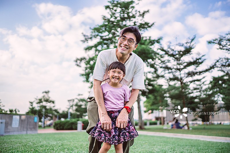 年轻帅气的爸爸在公园里开心地拥抱她的女儿图片素材