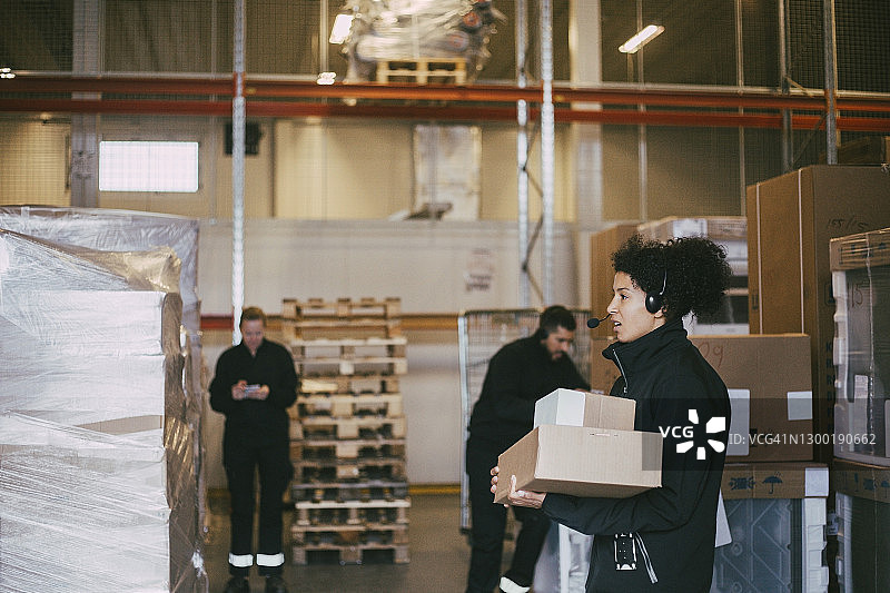 女企业家拿着包裹站在物流仓库的同事旁边图片素材