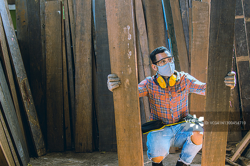 木匠在一间木工办公室工作。一位白人男木匠正在挑选木材，掸去木屑。图片素材