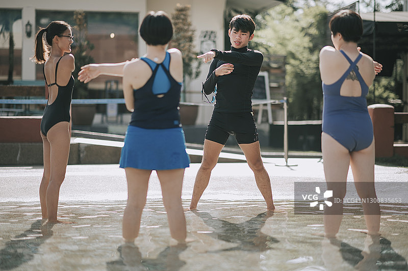 中国男教练教练在游泳池游泳课前做热身运动图片素材