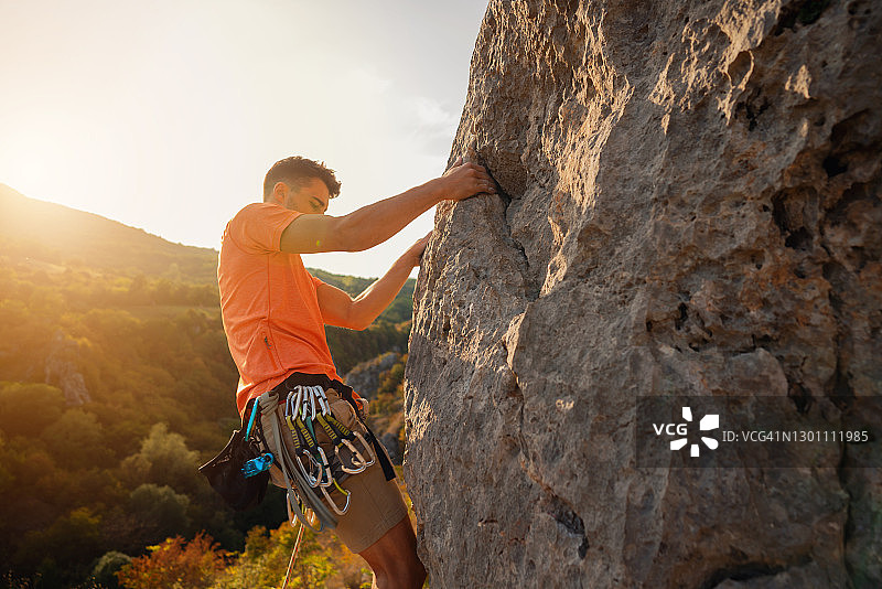 一个年轻登山者在岩石山上的侧视图图片素材