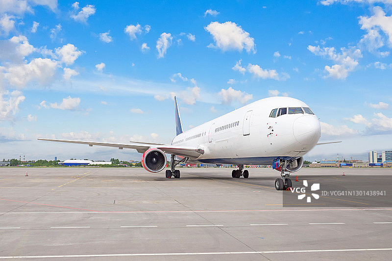飞机停在机场，背景是蓝色的天空和白云。世界航空的概念。图片素材