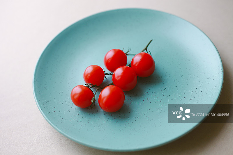 新鲜生红樱桃番茄蔬菜在蓝色盘子图片素材