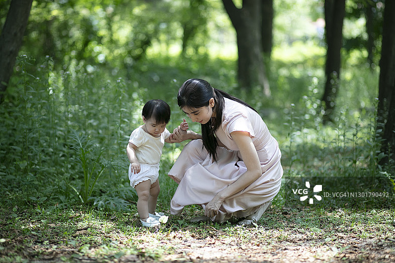 和妈妈在公园散步时，宝宝盯着草地看图片素材