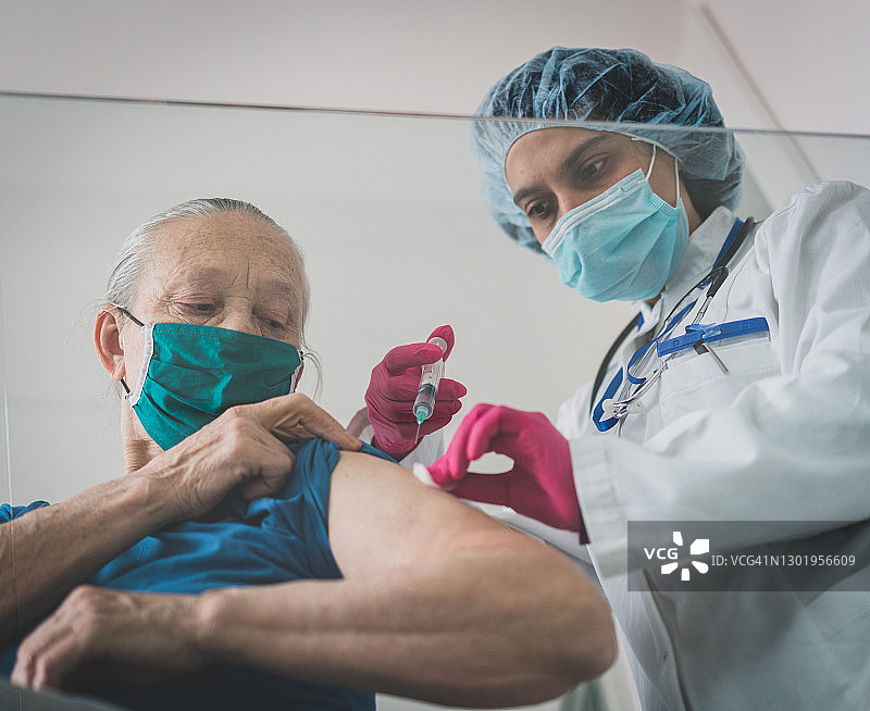 医生戴口罩为年长妇女接种疫苗图片素材