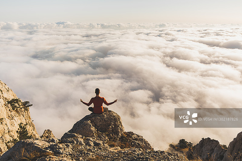 一个人在山上独自练习瑜伽，可以看到很低的云图片素材