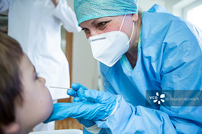 医护人员穿着防护服从病人的鼻子上取样。图片素材