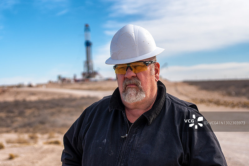 石油钻机工人与石油或天然气钻井平台在远处摆姿势图片素材