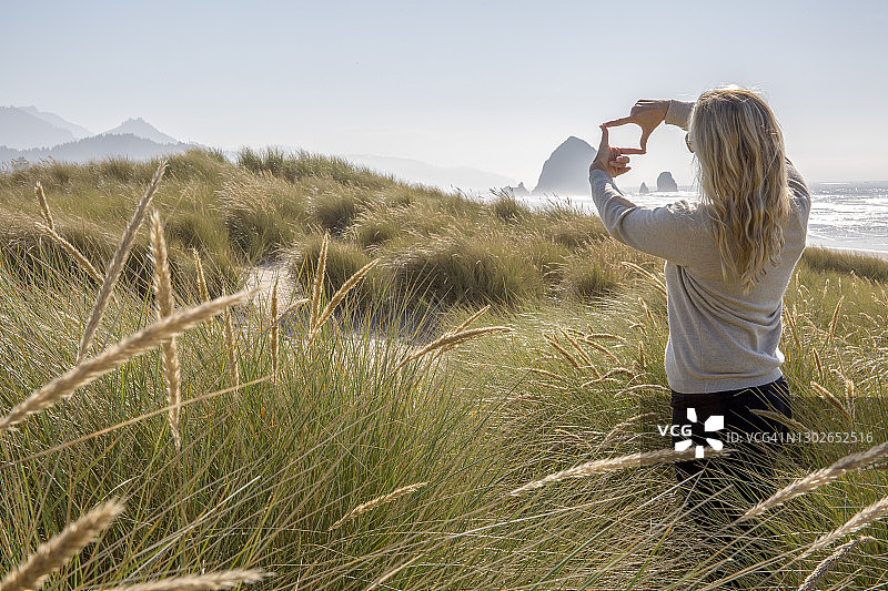 清晨，一名妇女在海岸线上的草地上放松图片素材
