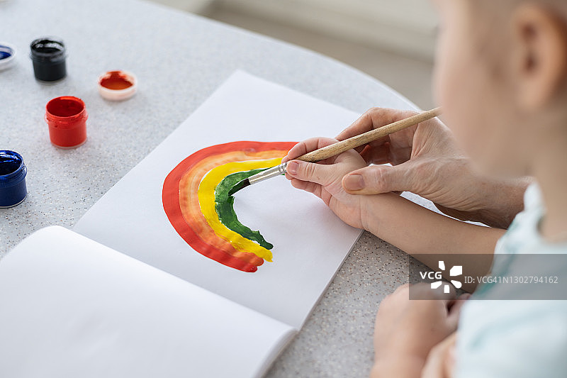 孩子的手在大人的手里学会画彩虹图片素材