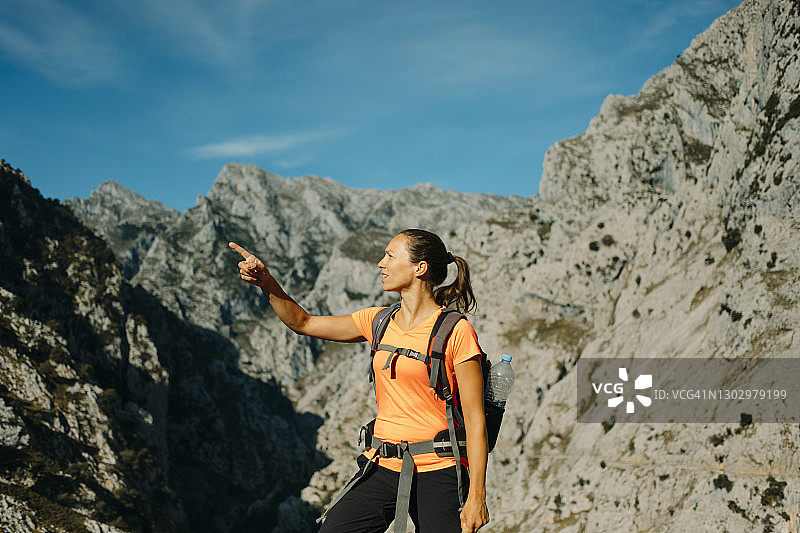 西班牙阿斯图里亚斯的Picos De Europe国家公园，一名中年妇女站在山脉前打手势图片素材