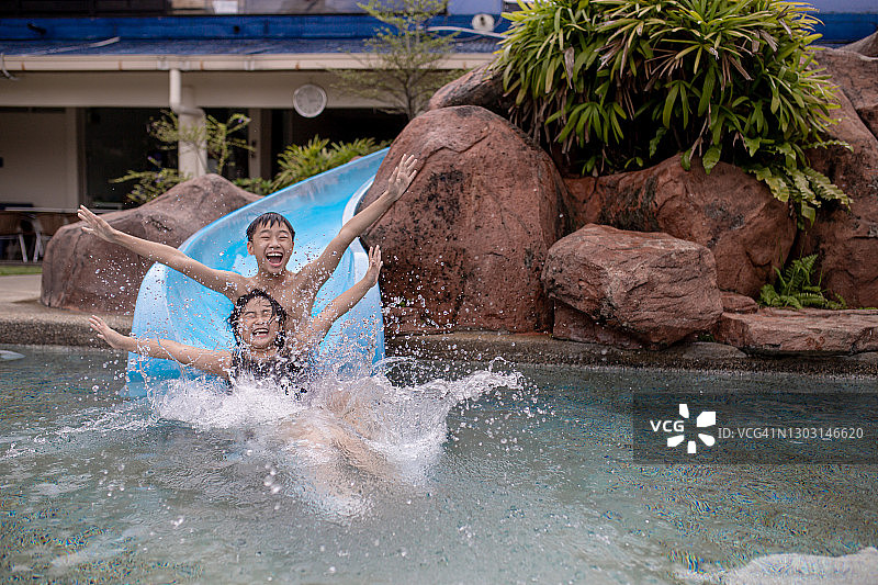 亚洲华人儿童享受滑水在游泳池在周末假期的乐趣时间图片素材