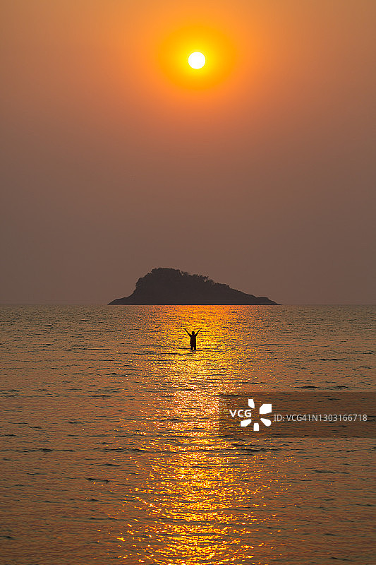 泰国Koh Chang岛的海滩，一个女人的剪影在大海和一个岛屿后面的下午日落前。图片素材
