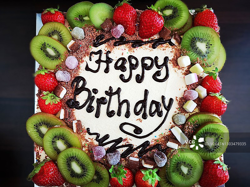 生日蛋糕上面写着字，周围装饰着许多新鲜的水果图片素材