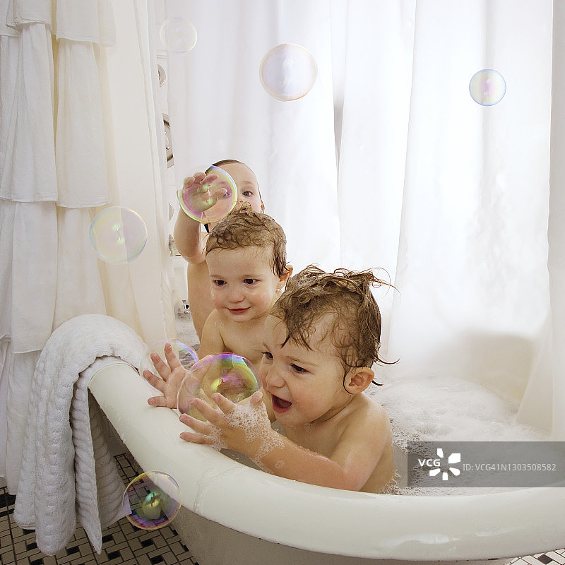 婴儿在浴缸里玩泡泡浴。图片素材