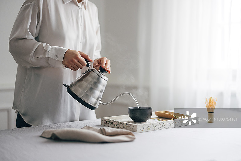 健康的早晨习惯:一个年轻女人在家里准备抹茶图片素材