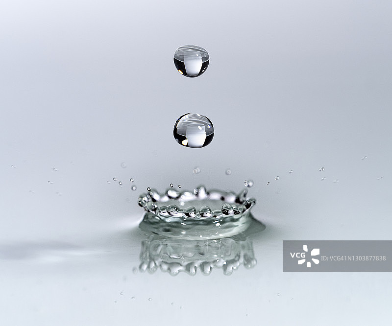 一组水滴在白色背景的液体表面上的影响。图片素材