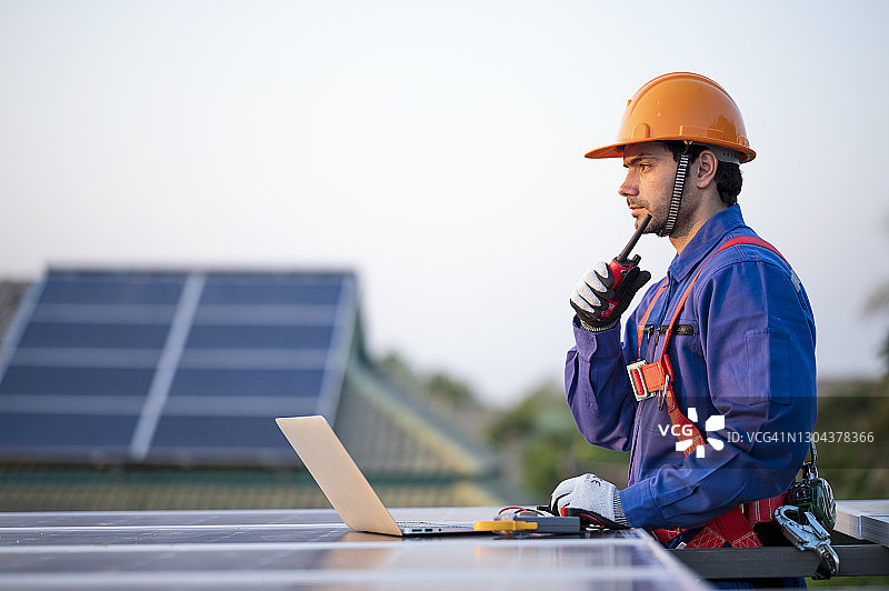 男工程师正在屋顶安装太阳能电池板。选择,可持续能源。图片素材