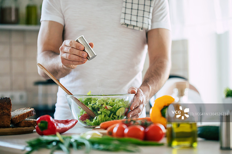 近距离照片的年轻男性的手正在准备奇妙的新鲜的素食沙拉在厨房在家里图片素材