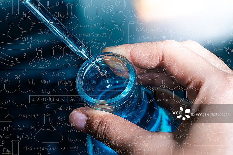 手握烧瓶与实验室玻璃器皿和试管在化学实验室的背景，科学实验室研究和发展的概念图片素材