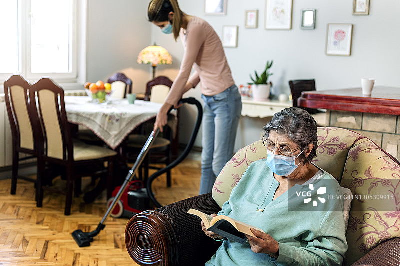 为老年妇女打扫房子的家政助手图片素材