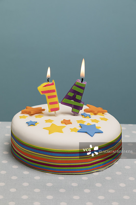 上面点着14支蜡烛的生日蛋糕。图片素材